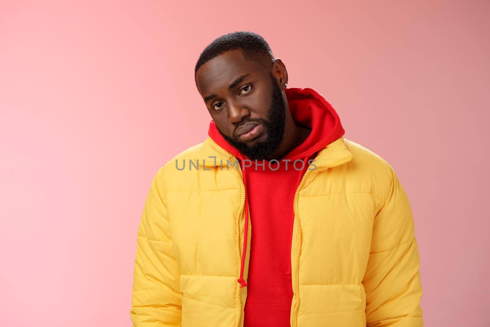 Unimpressed bored ignorant young african bearded man tilt head look scorn uninterest camera listen boring useless information, standing careless in yellow jacket red hoodie, indifferent.