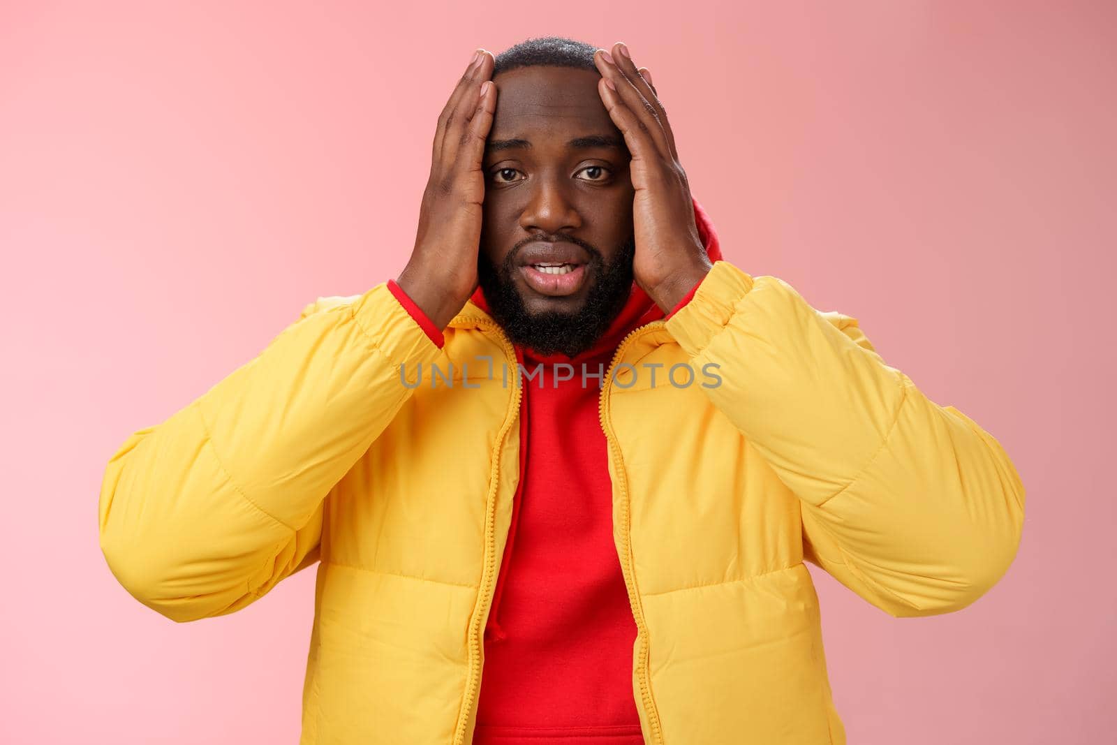 Shocked upset african-american bearded guy feel regret stunned hear terrible news hold hands head widen eyes stupor standing speechless troubled, look perplexed terribly sad, pink background.