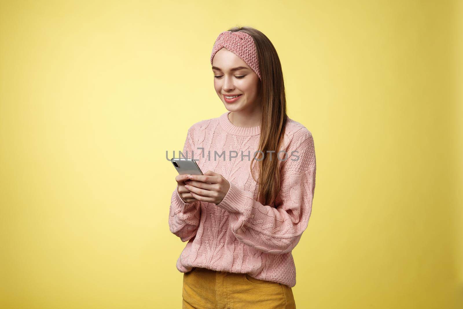 Girl chatting, texting, sending funny emoji friend smiling entertained holding smartphone looking device screen amused, enjoying playing with awesome app, watching video online via cellphone by Benzoix