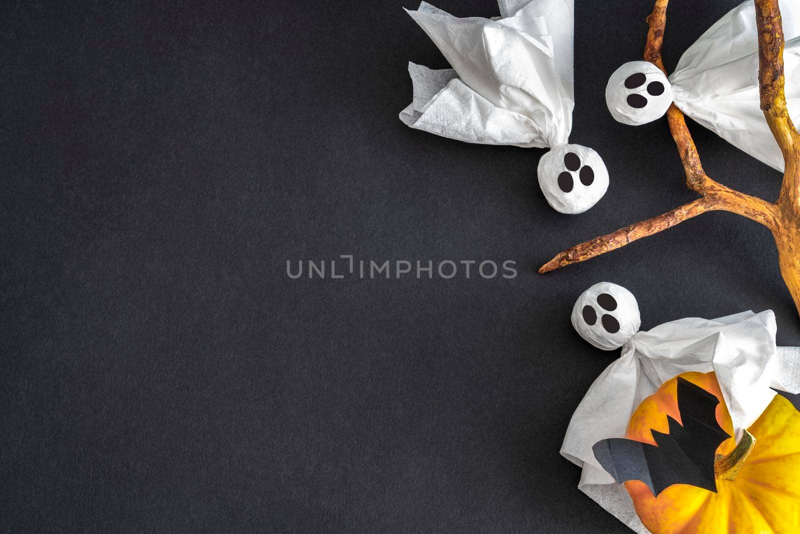 Three ghosts, bat and pumpkin on black background. Halloween symbols. Copy space.