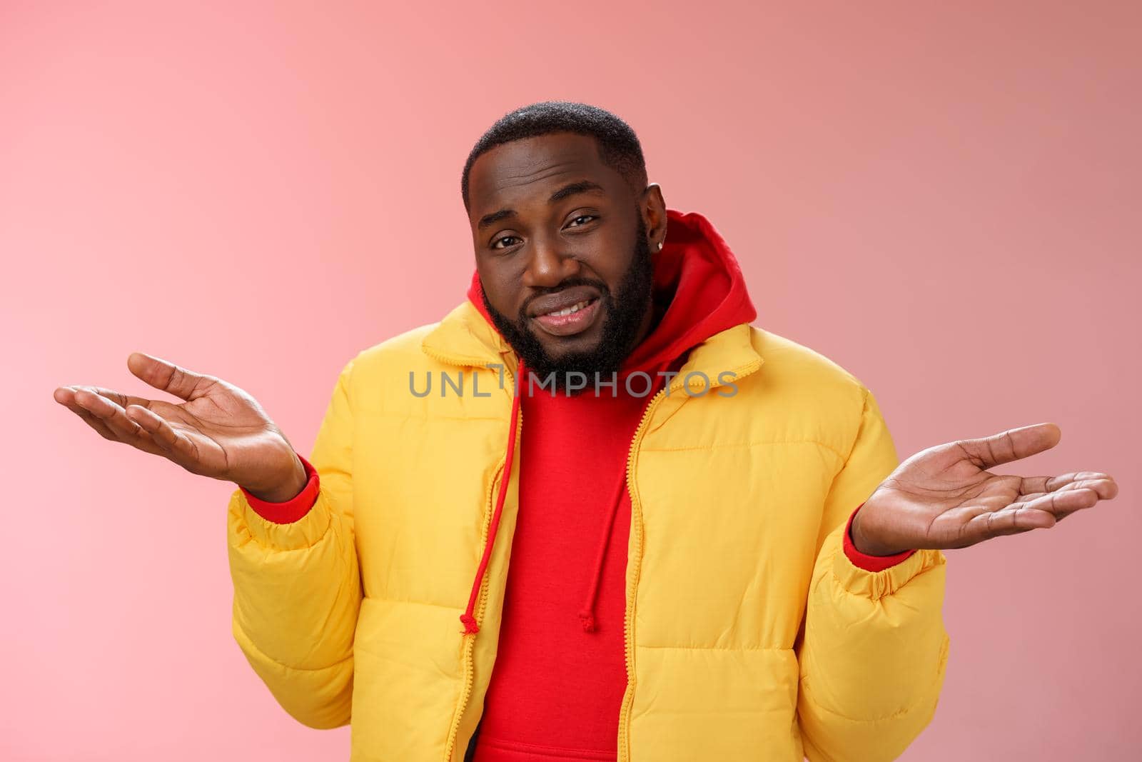 Close-up clueless unaware handsome stylish african-american bearded man in yellow jacket shrugging hands spread sideways dismay cannot understant anything standing perplexed, pink background by Benzoix