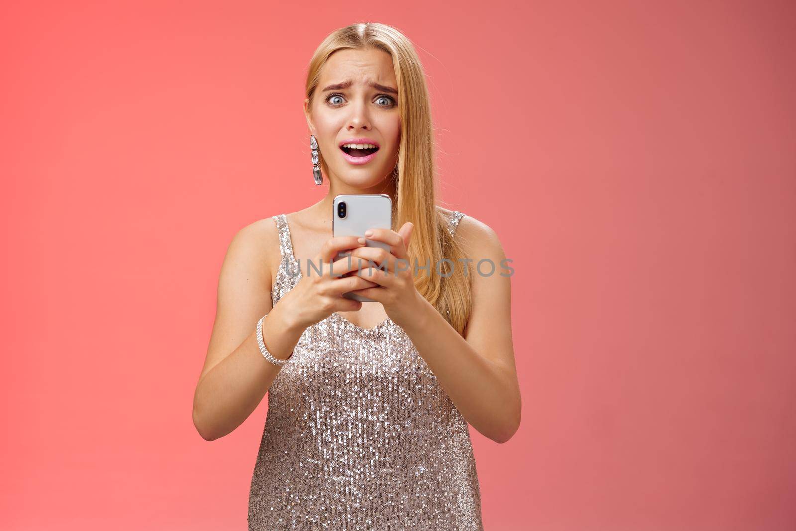 Panicking shocked woman concerned photos leaked internet look afraid anxious widen eyes cringing troubled hold smartphone shook speechless gasping terrified friends find out secret, red background.