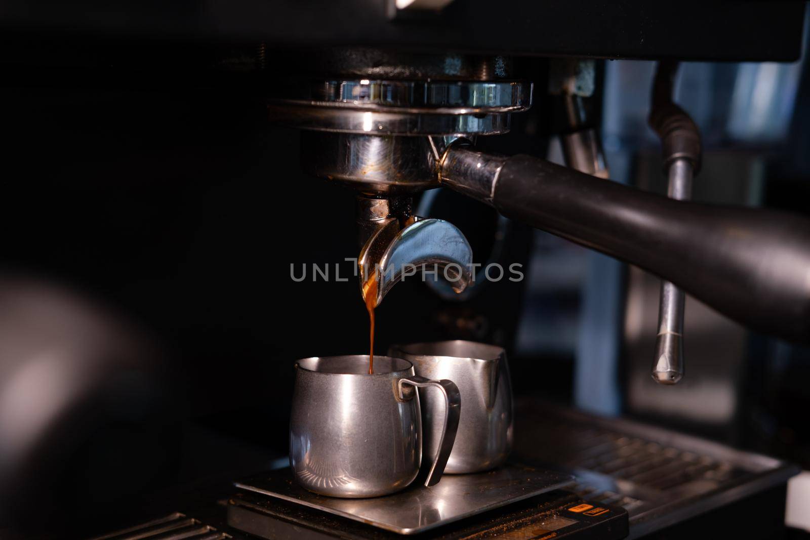 black coffee is pouring from professional coffee machine. coffee making by barista. dark loft coffee shop.