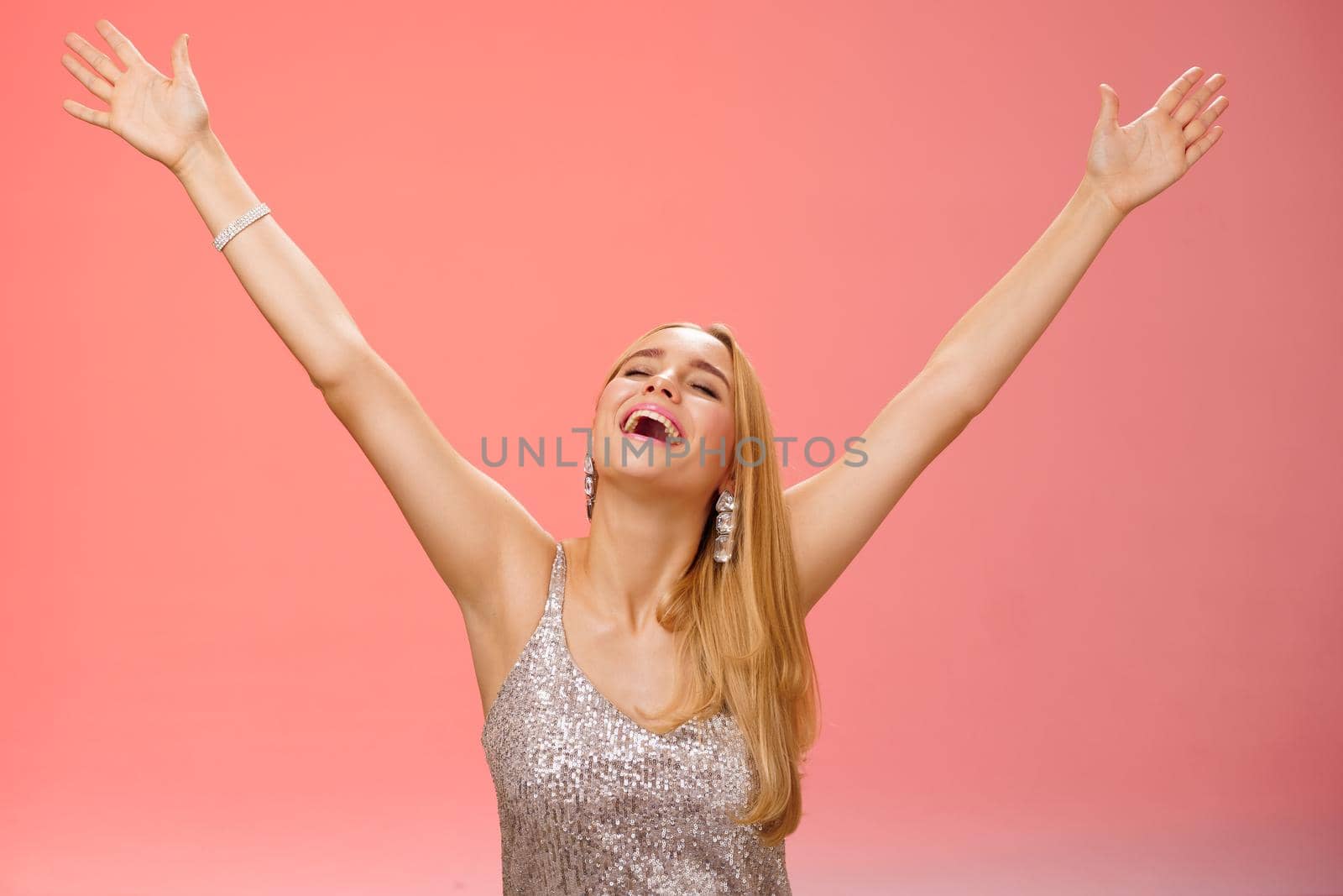 Waist-up carefree happy girl fulfill dream raising hands up sky joyfully close eyes smiling celebrating good perfect news triumphing achieve success victory, standing thrilled red background.