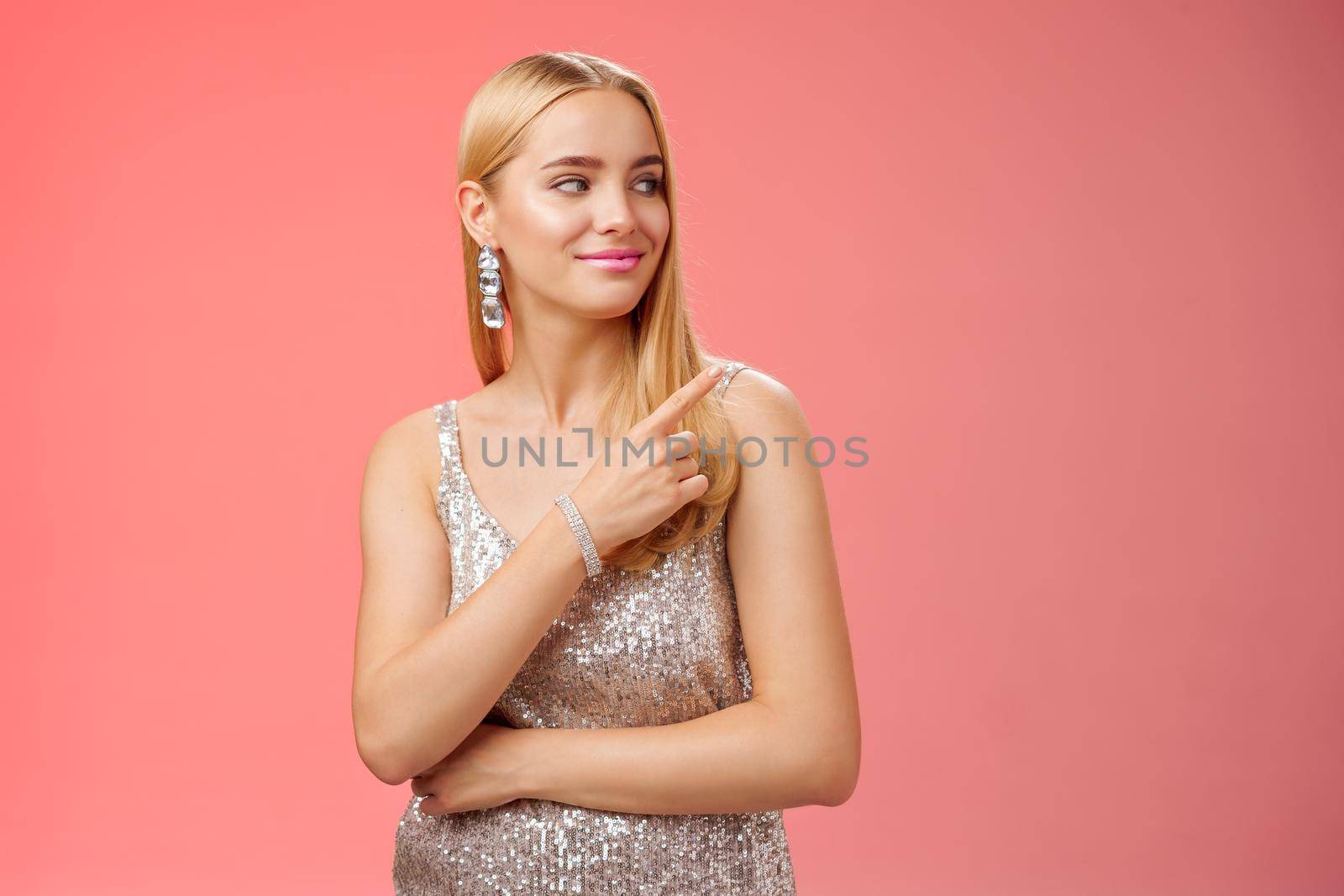 Confident tender carefree charming blond girl party in silver shiny glamour dress pointing looking right assured delighted point bar boyfriend order drinks nightclub, standing red background.