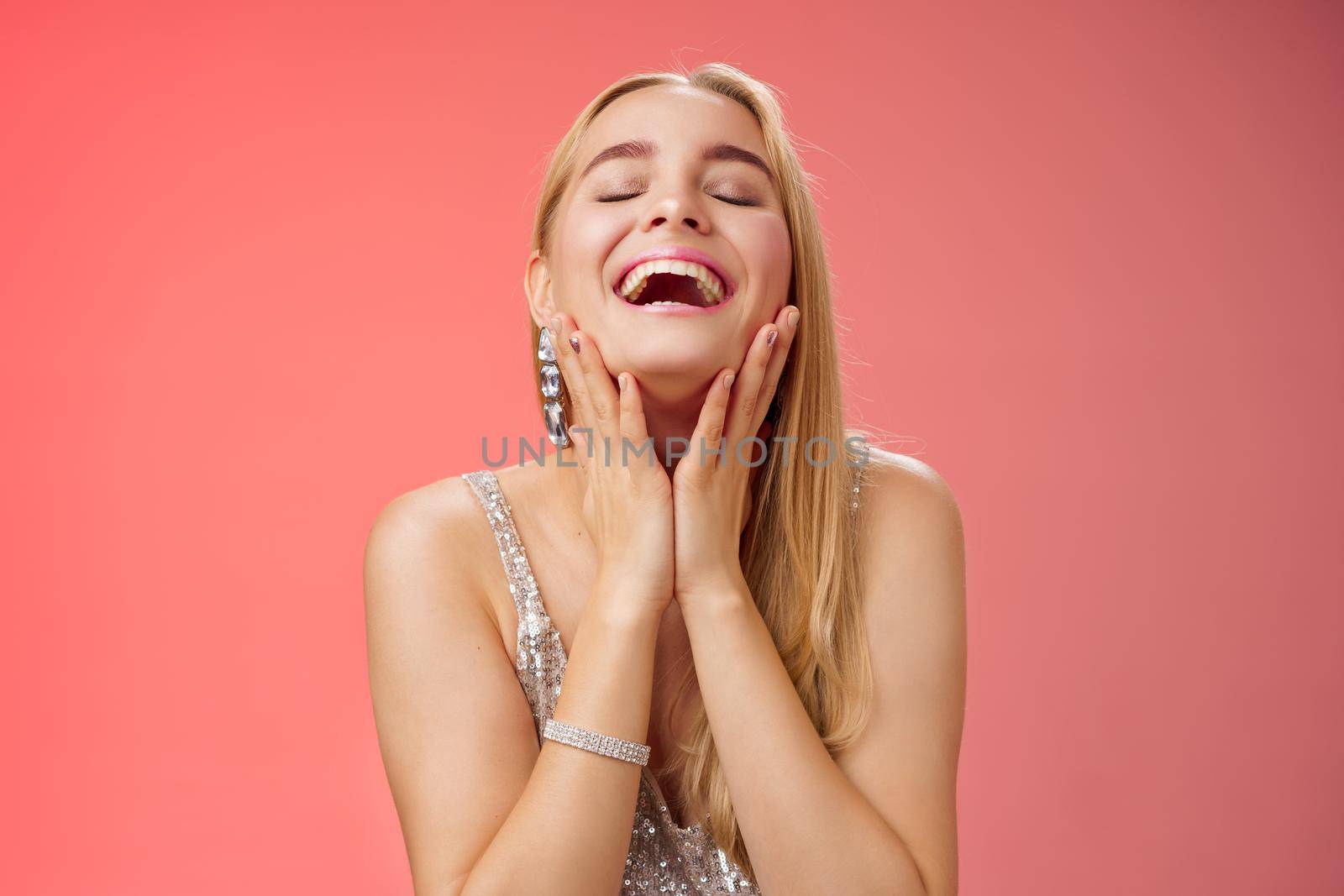 Waist-up joyful accomplished charming rich blond woman in silver stylish evening dress touching cheeks happily smiling laughign carefree close eyes tender have fun relaxing party dance floor by Benzoix