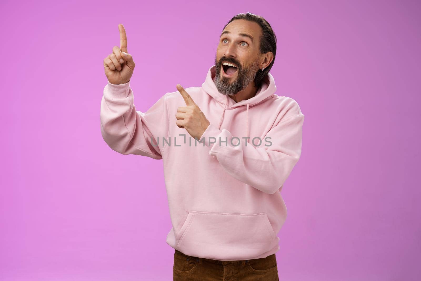 Fashionable good-looking fascinated mature bearded man grey hair look astonished pointing gazing upper left corner see miracle incredible breathtaking magnificanent view, standing purple background by Benzoix