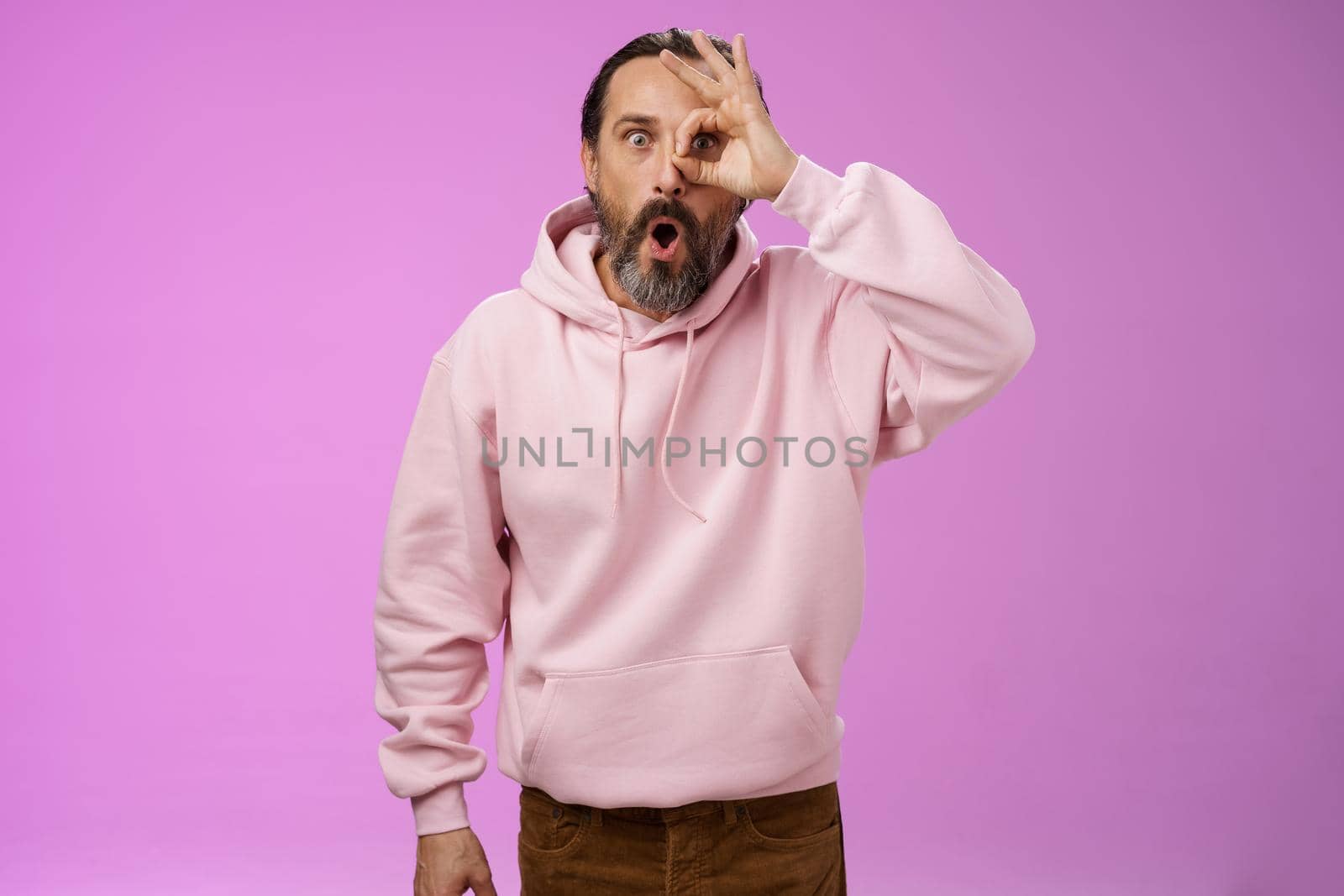 Impressed speechless handsome stylish old man bearded grey hair say wow drop jaw see incredible discount show okay ok excellent gesture eye look through amazed, standing pleased purple background by Benzoix