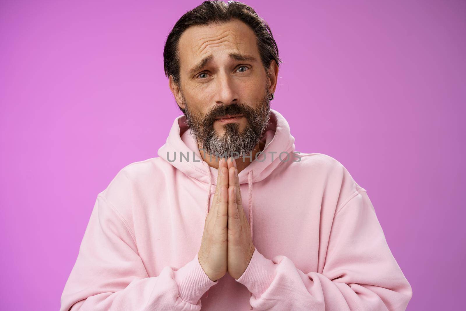 Upset handsome bearded mature man need help asking forgiveness supplicating press palms together praying frowning sorrow begging favour lend money, standing purple background miserable by Benzoix