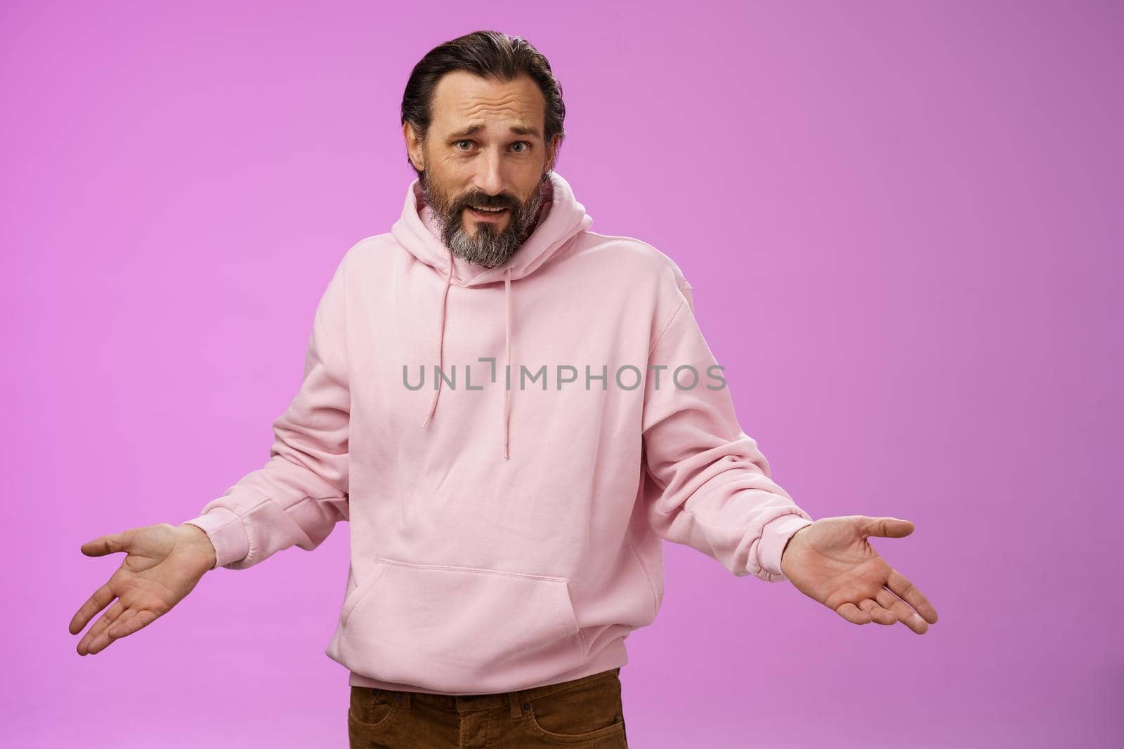 Bothered confused mature adult bearded man grey hair in pink hoodie arguing look pissed offended shrugging spread hands sideways dismay look clueless camera asking why, purple background by Benzoix