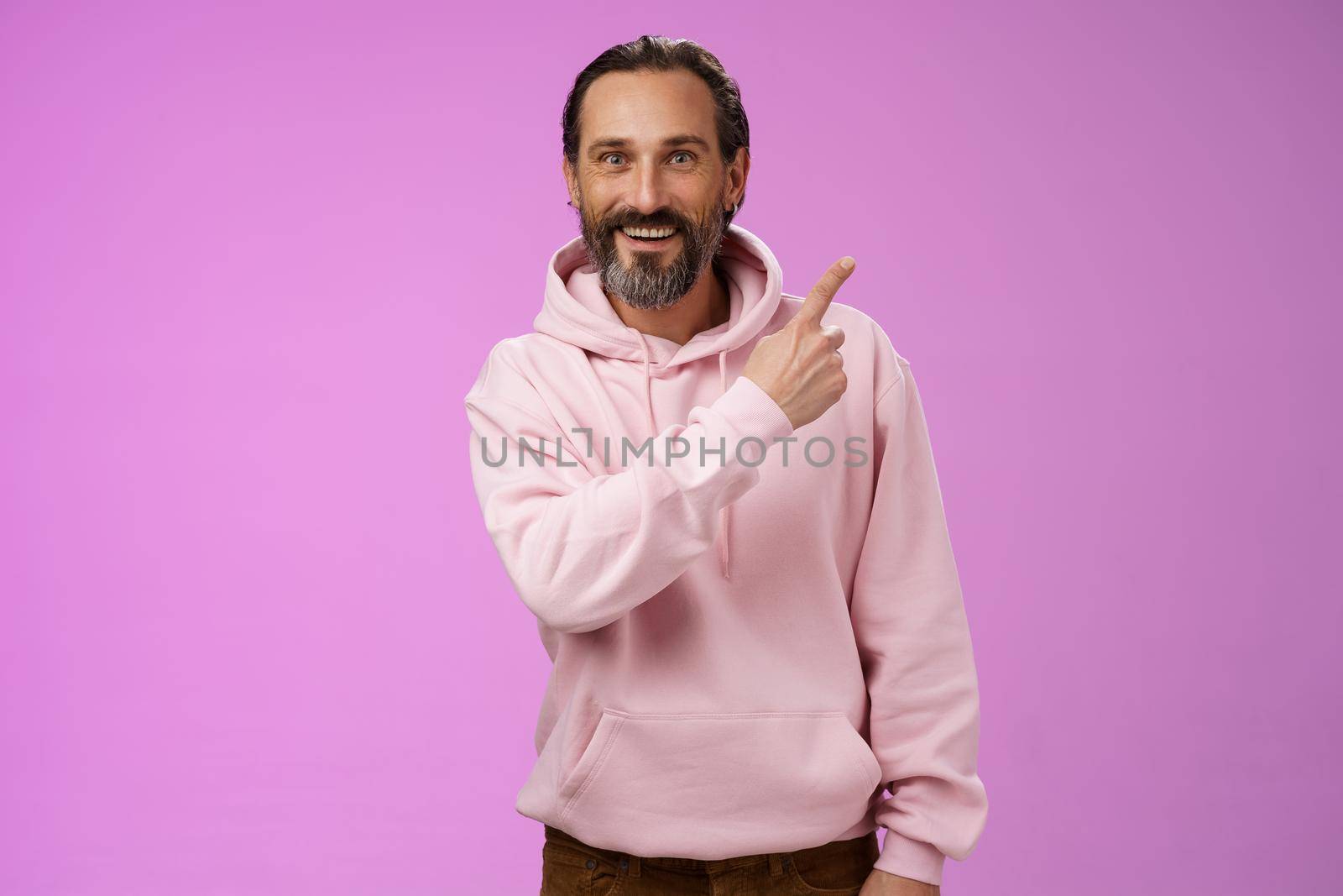 Good-looking lucky energized happy mature 50s man grey hair in trendy hipster hoodie pointing upper right corner amused telling you interesting news smiling white teeth thrilled joyfully look camera by Benzoix