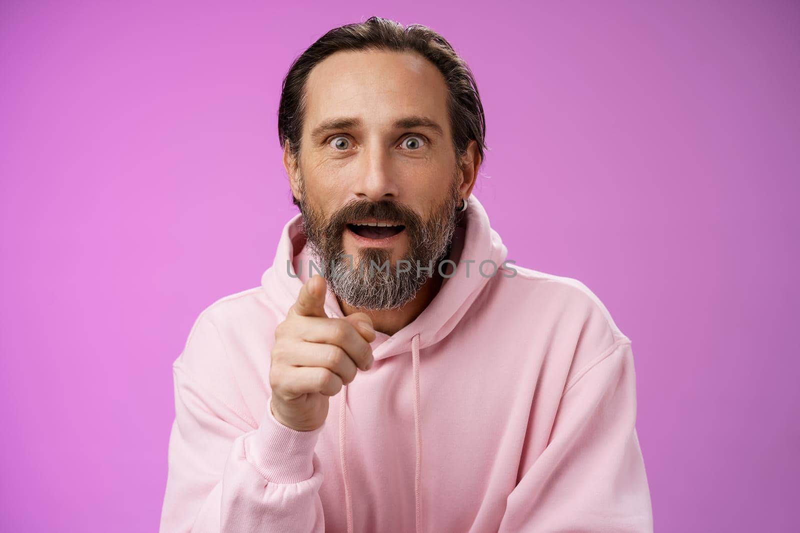 Fascinated amused european bearded mature guy widen eyes shocked open mouth recognize person pointing camera index finger surprised see familiar famous star, standing purple background by Benzoix