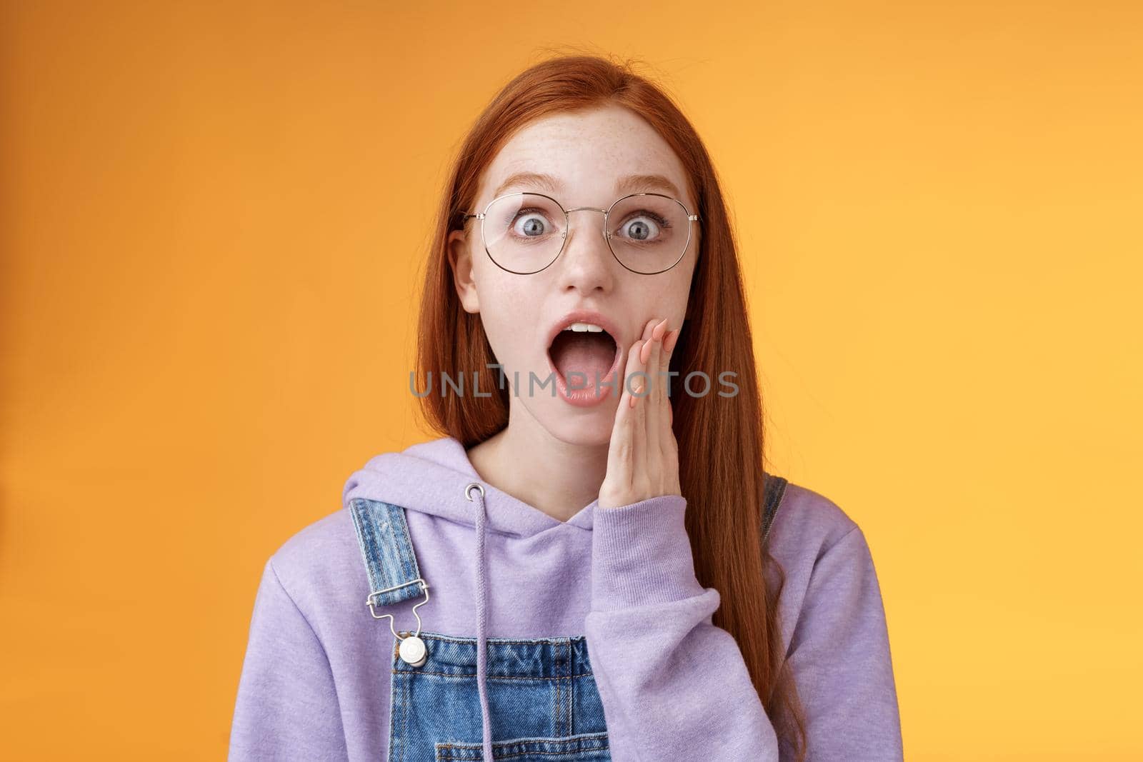 Omg no way. Attractive shocked wondered redhead amused hipster woman modern teenager drop jaw gasping wide eyes surprised standing amazed reacting shocked camera touch cheek excited by Benzoix