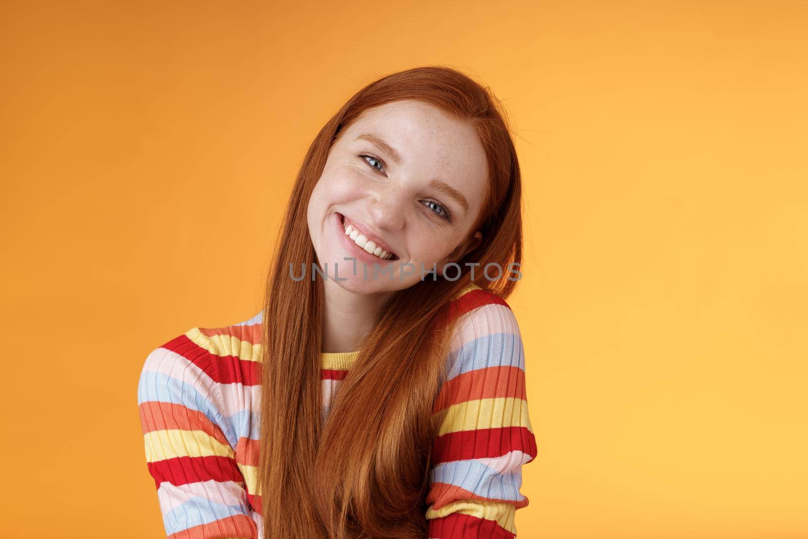 Lifestyle. Tender lively cheerful smiling redhead european girl 20s tilting head leaning shoulder flirting grinning cute make lovely gazes camera coquettish talking boyfriend standing silly orange background.