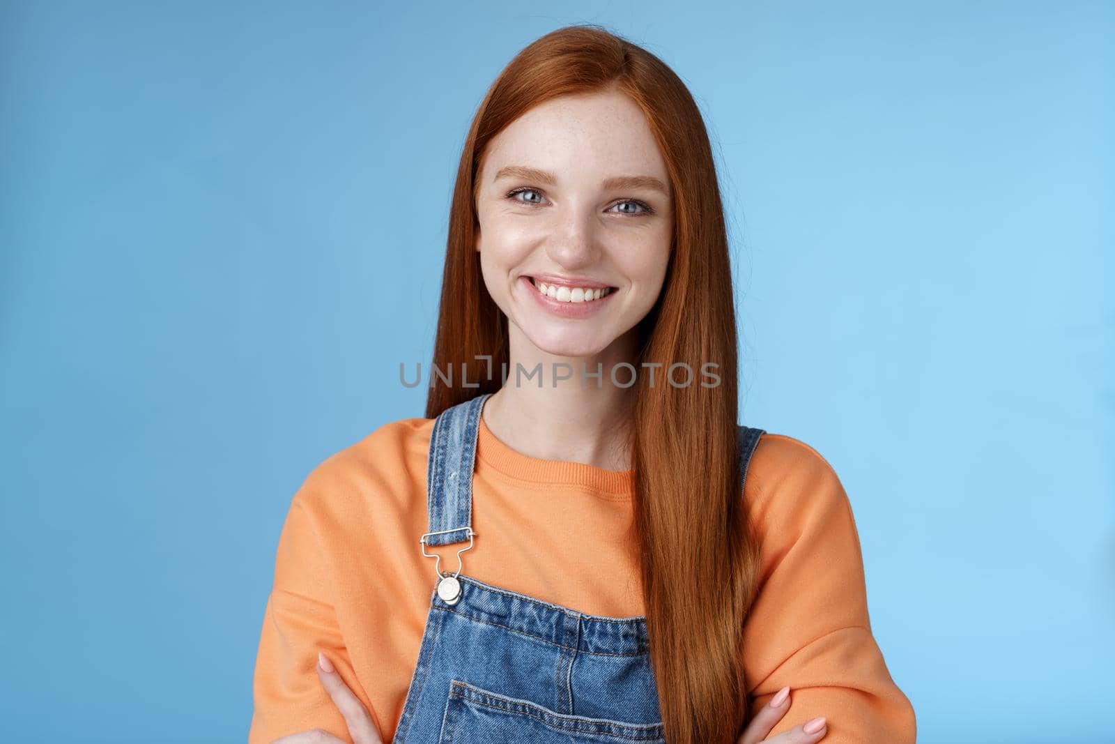 Young stylish confident smiling female redhead freelancer assured job done great grinning satisfied hold hands crossed chest self-assured standing blue background good mood upbeat attitude by Benzoix