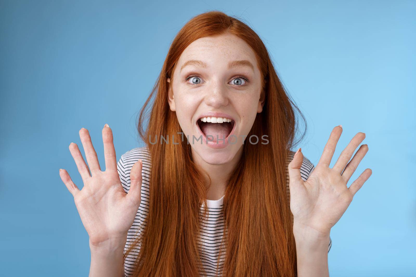 Excited charismatic happy lively redhead young funny woman smiling thrilled open mouth fascinated wide eyes surprised staring adore cool new product raise palms waving hello, show ten dozen.