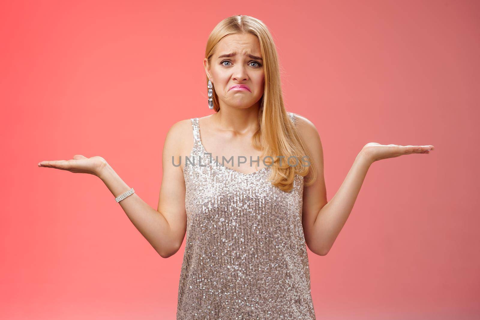 Upset clueless frustrated blond european young girl in glittering silver evening dress grimacing pouting sad shrugging raise hands sideways dismay doubtful, no idea what do, complicated decision.