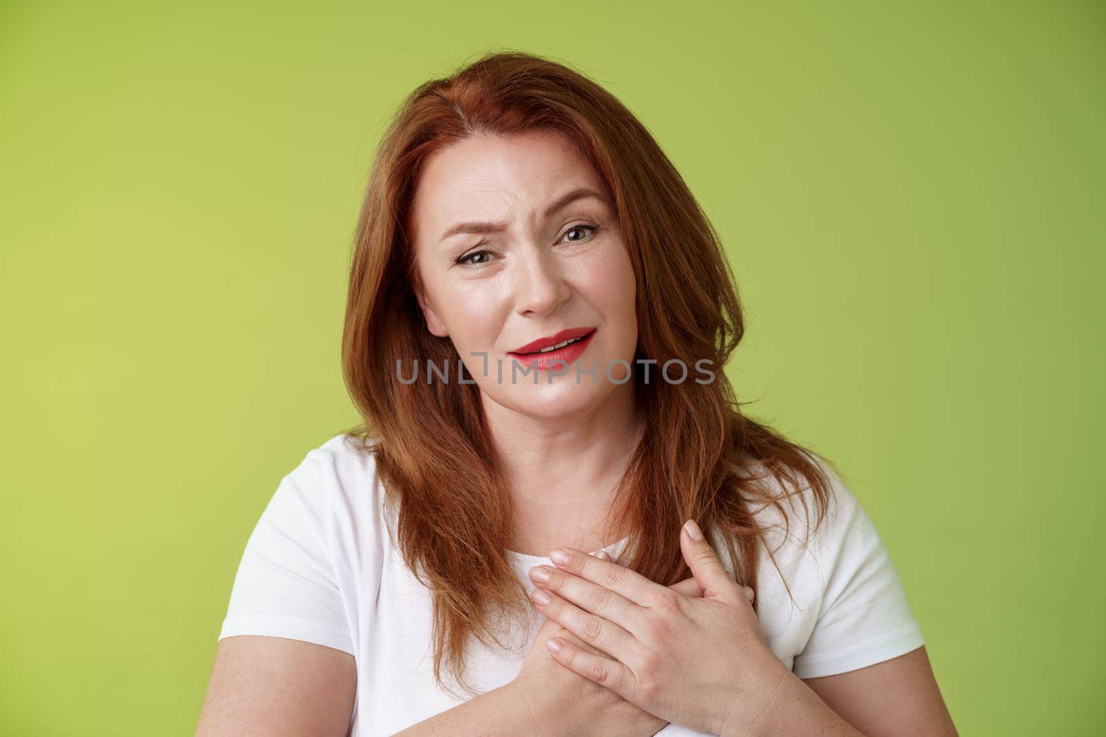 Story touched lady heart. Tender impressed middle-aged redhead woman press palms chest sighing happily look heartwarming temptation smiling appreciate nice gesture grateful thanking dearly.