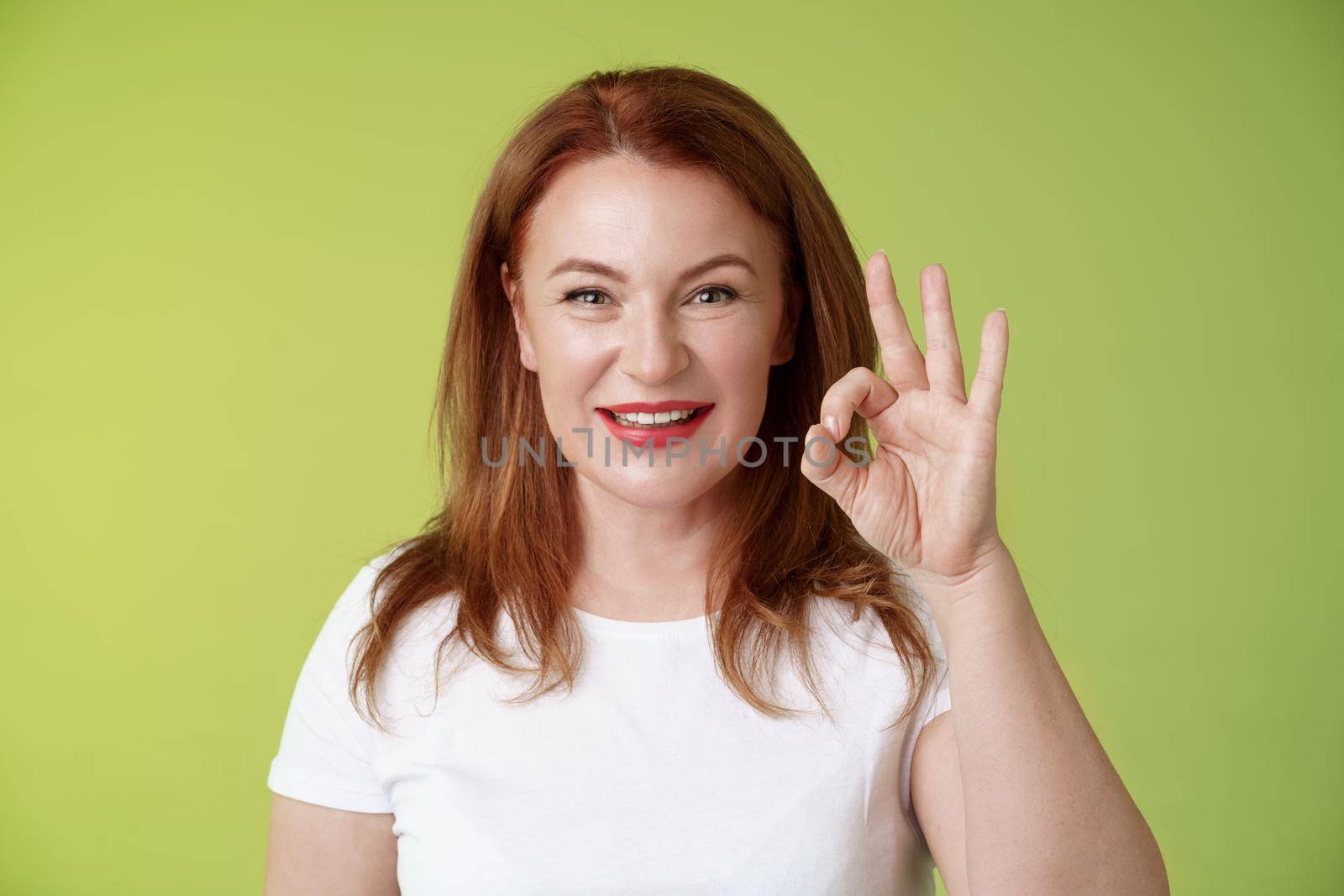 Alright got it. Cheerful motivated determined redhead enthusiastic middle-aged woman show okay ok confirm gesture assured smiling satisfactory gesture give positive like approval green background by Benzoix