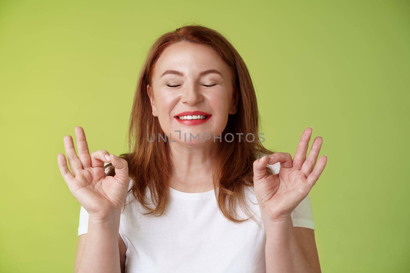 Close to perfection. Close-up peaceful relaxed redhead happy woman closed eyes pure delighted smile show zen peace satisfaction gesture meditating reach nirvana calm stand green background by Benzoix