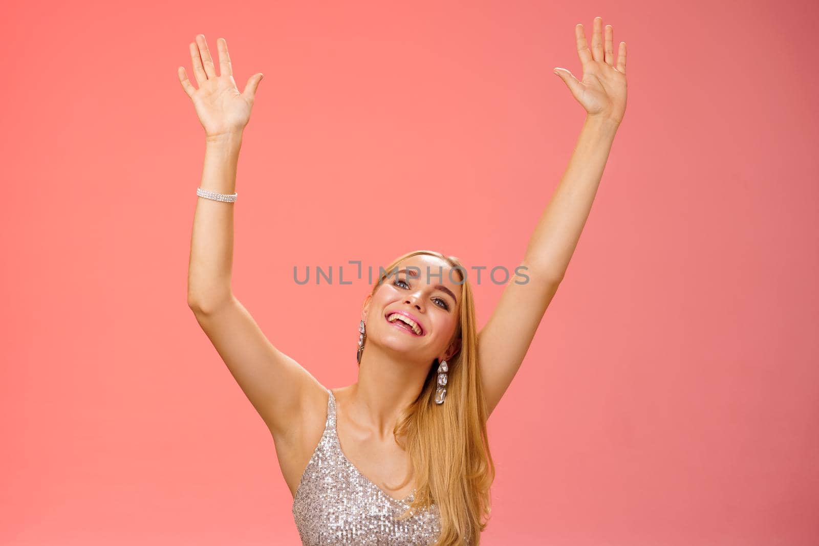 Lifestyle. Girl dancing having fun standing fan-zone party enjoying awesome concert favorite singer in silver glittering elegant dress raise hands up waving palms moving music rhythm smiling delighted.