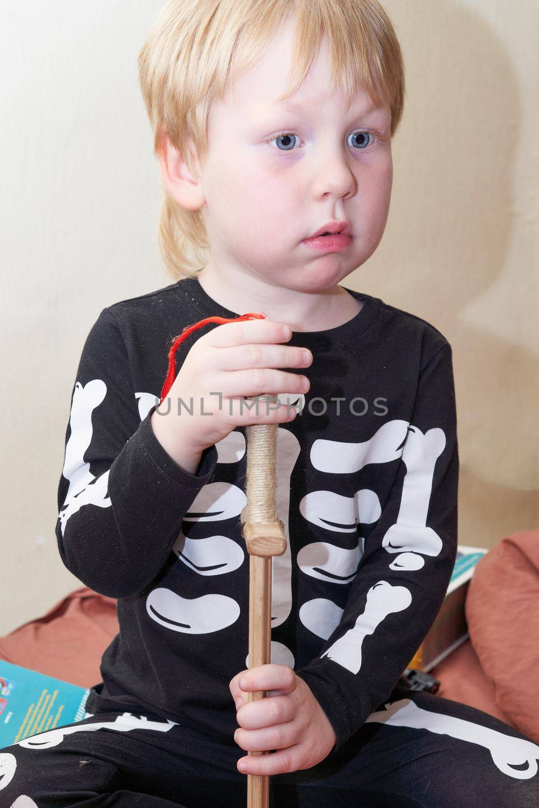 A child in a skeleton costume with a wooden sword sits on the couch by vizland