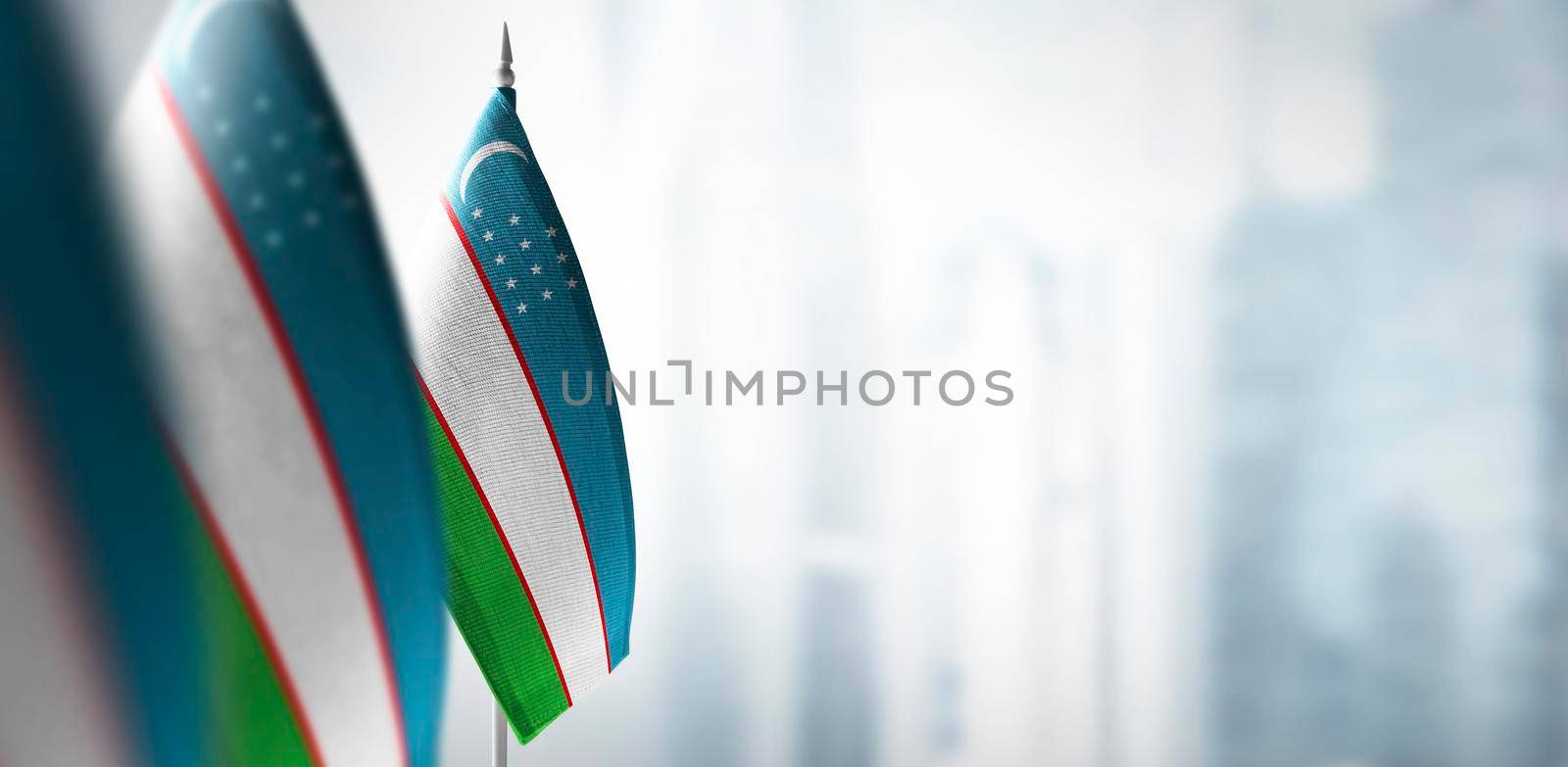Small flags of Uzbekistan on a blurry background of the city.