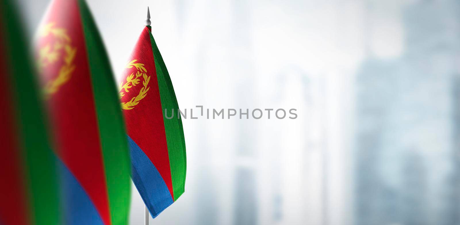 Small flags of Eritrea on a blurry background of the city.