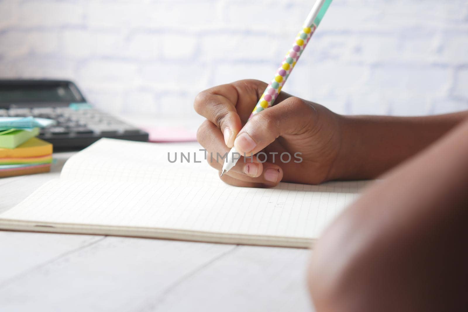 6 year old child girl hand writing on notepad sitting on a chair