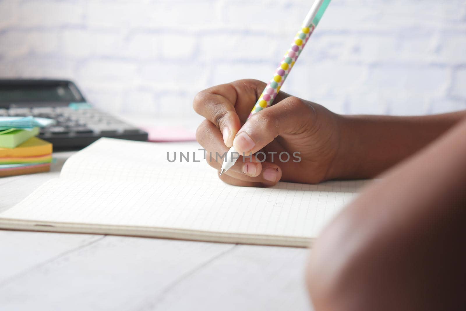 side view of child girl hand writing on notepad. by towfiq007