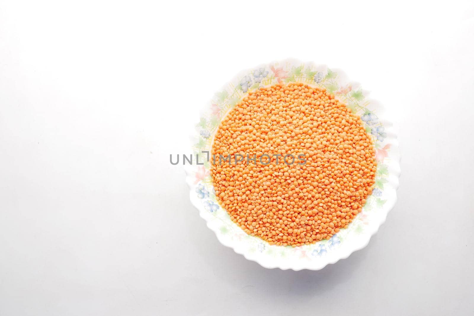 Bowl of uncooked dhal on white, by towfiq007