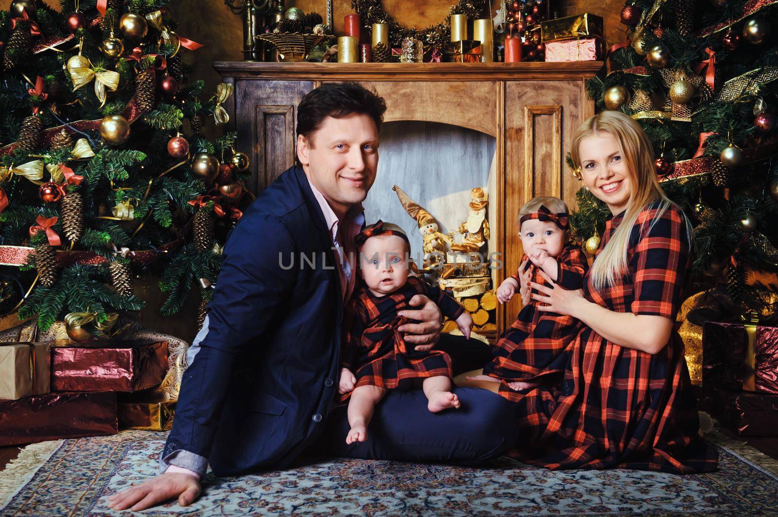 A happy big family with their children in the New Year's interior of the house by the fireplace next to the Christmas tree by Lobachad