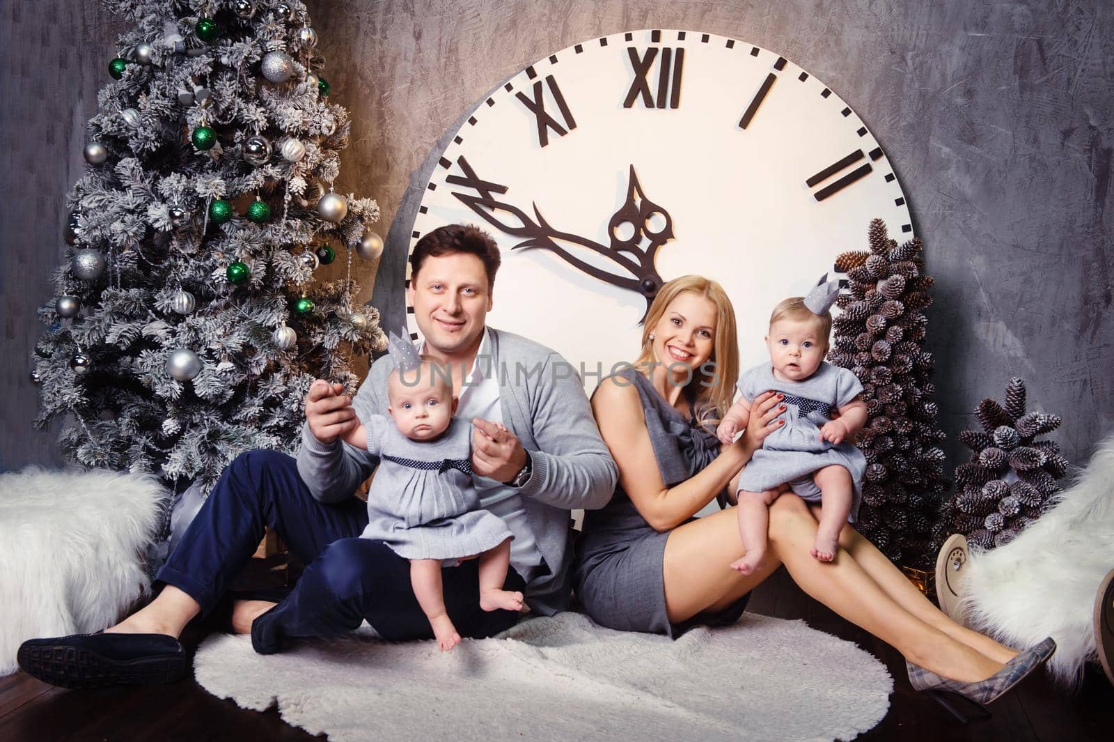 A happy big family with twin children in the New Year's interior of the house against the background of a large clock by Lobachad