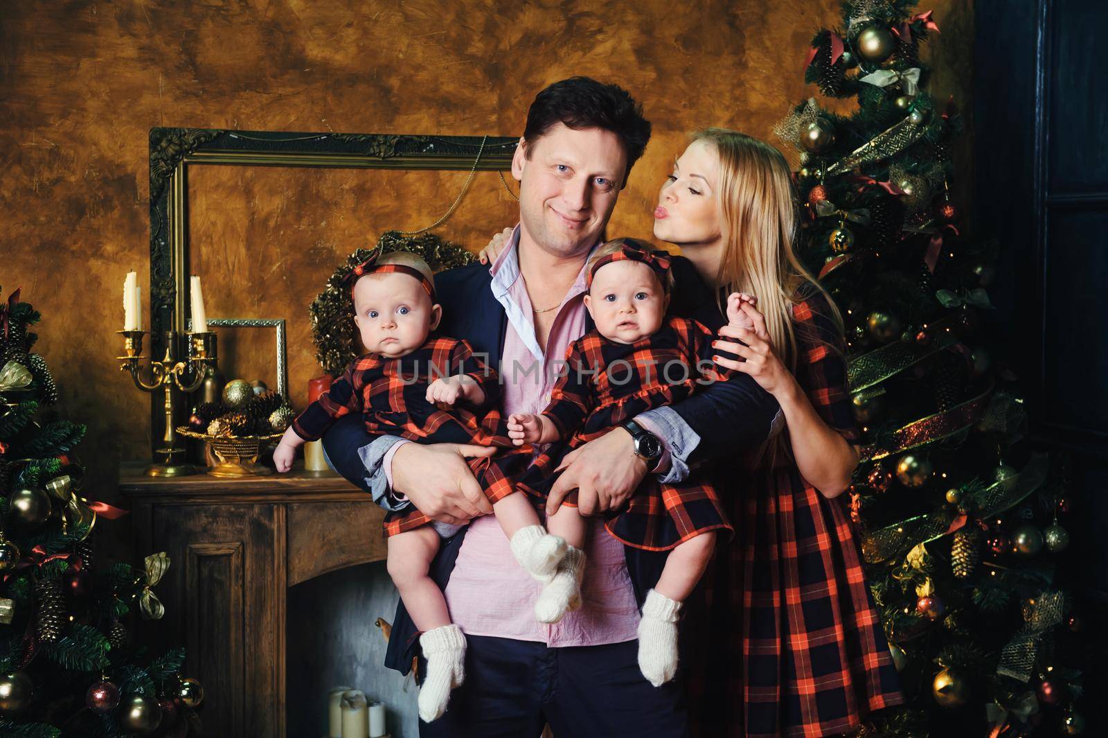 A happy big family with their children in the New Year's interior of the house by the fireplace next to the Christmas tree.