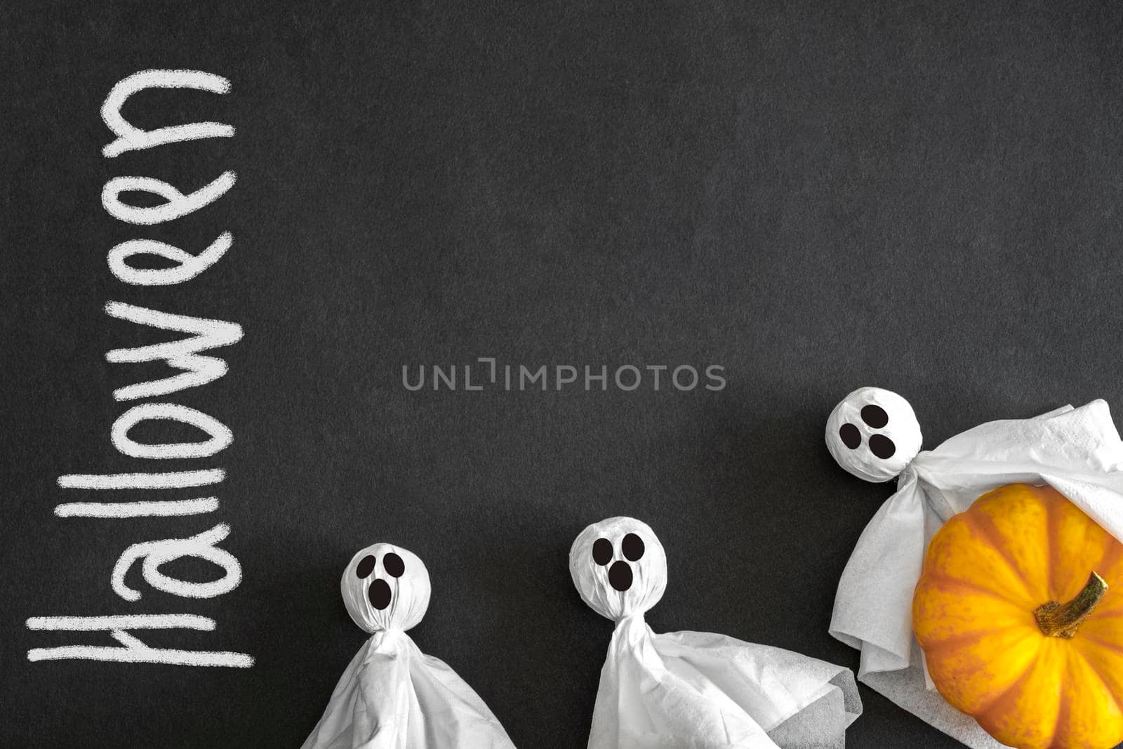 Ghosts and pumpkin, black background, inscription helloween, top view. Halloween Concept. Copyspace.