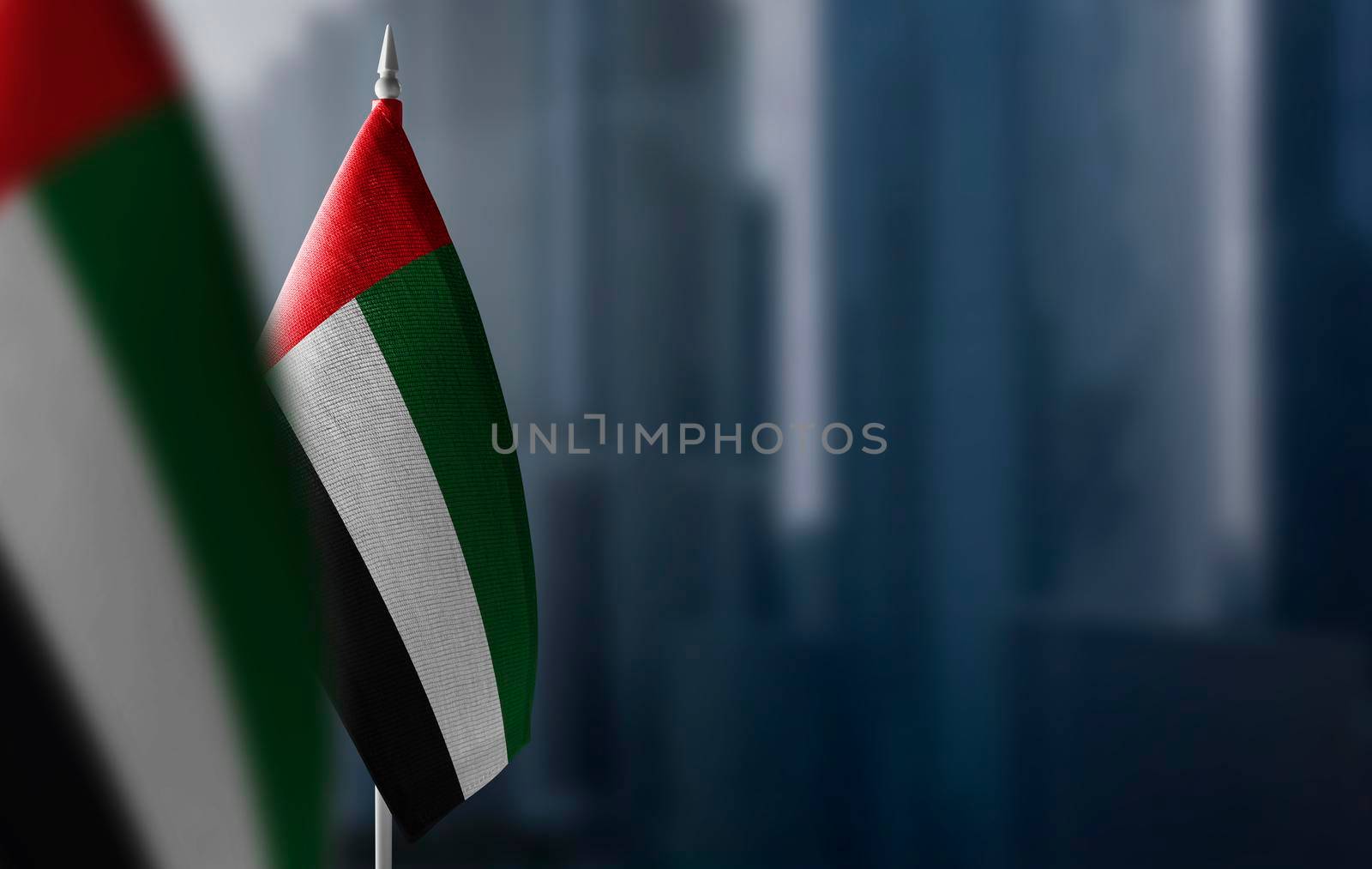 Small flags of United Arab Emirates on a blurry background of the city.