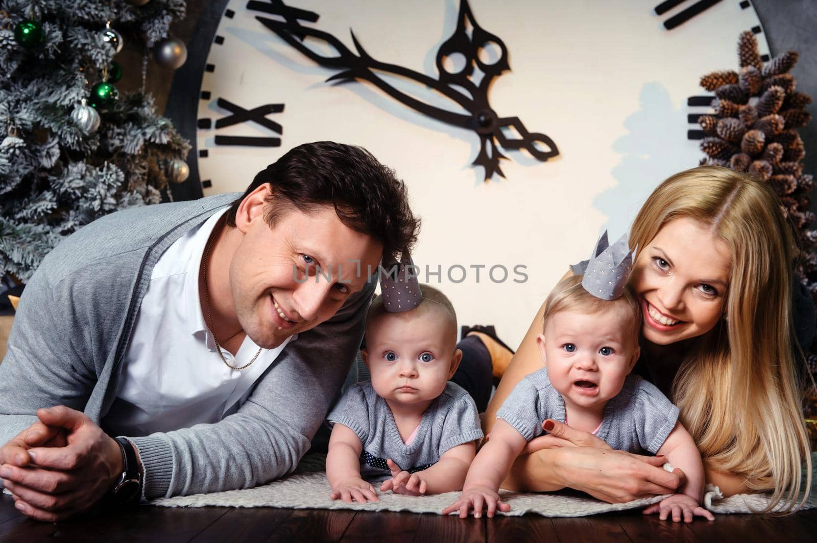 A happy big family with twin children in the New Year's interior of the house against the background of a large clock by Lobachad