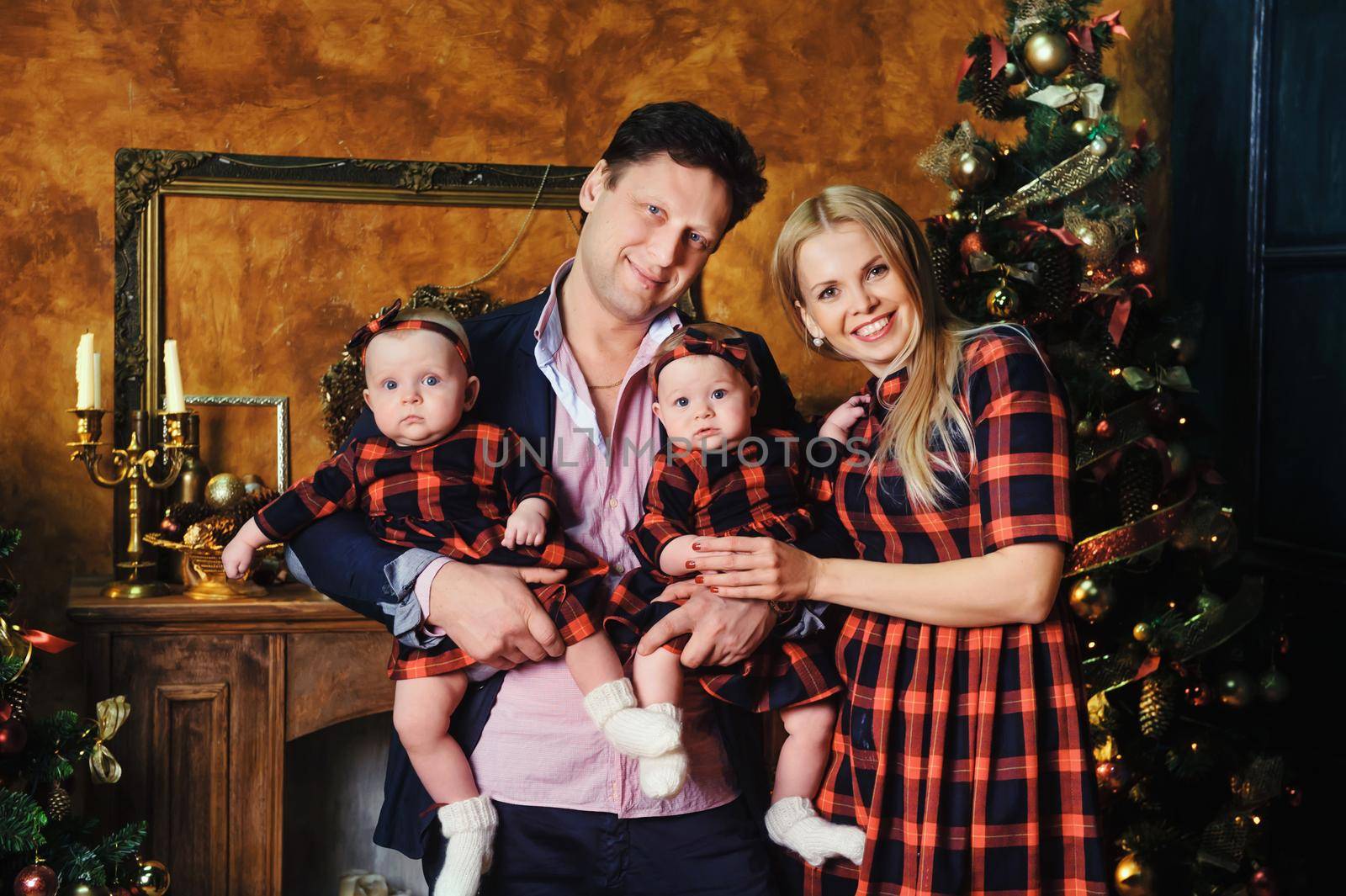 A happy big family with their children in the New Year's interior of the house by the fireplace next to the Christmas tree.