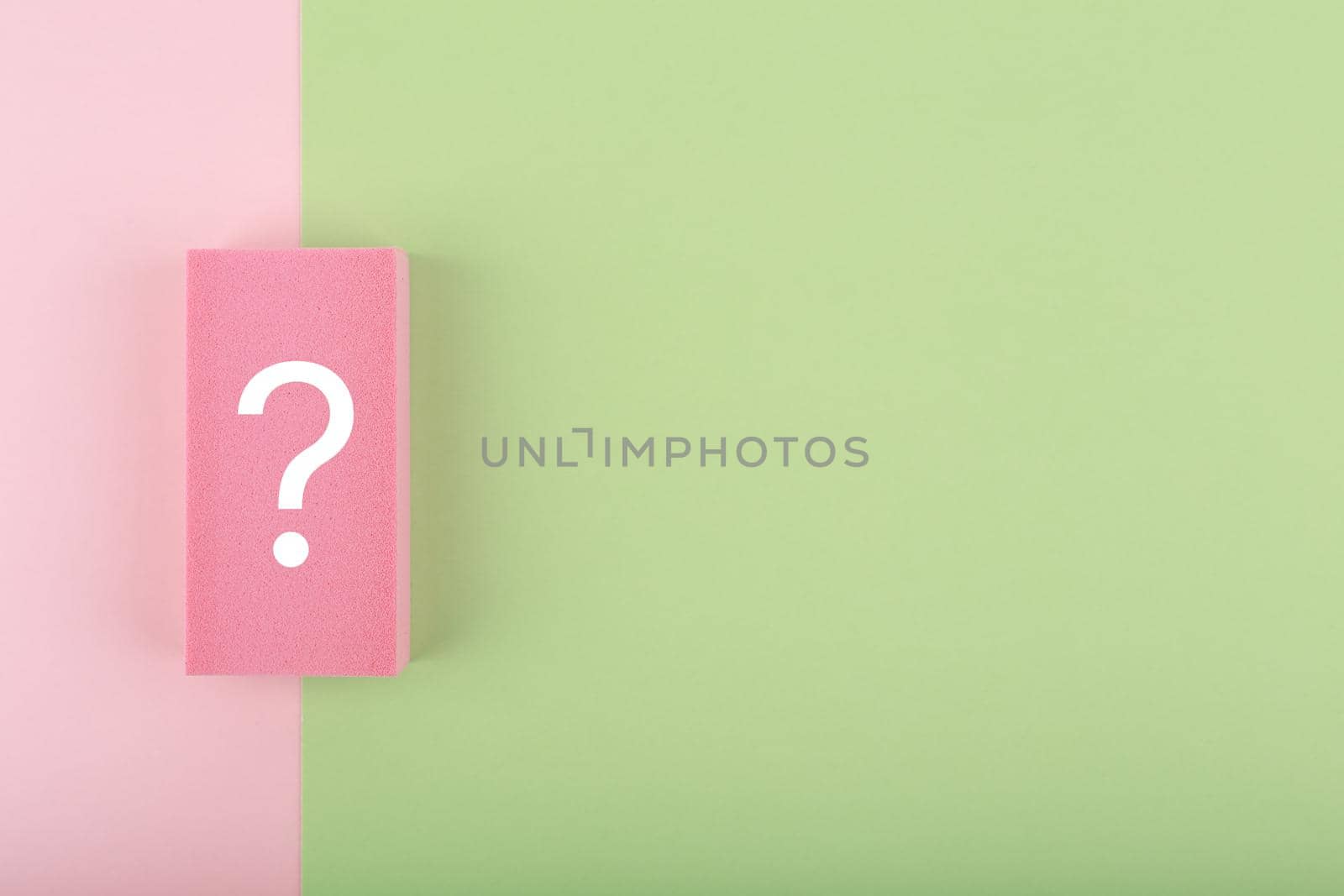 White question mark on colored pink and green background with copy space. Flat lay, trendy minimal composition with question