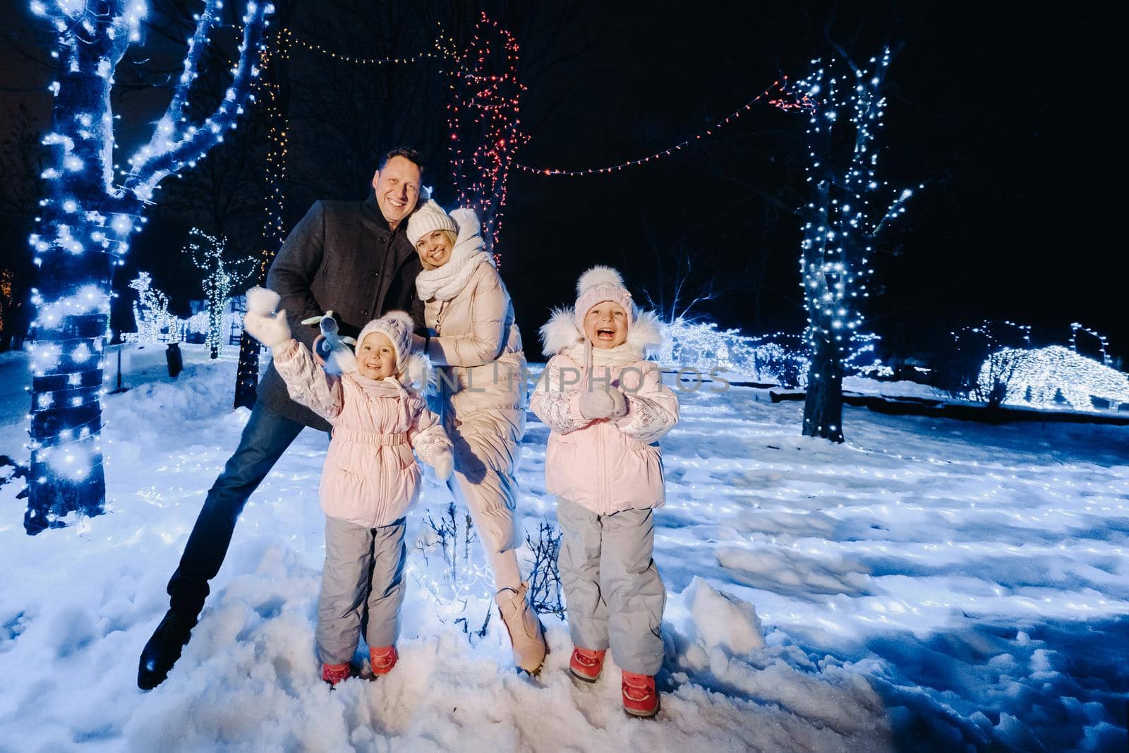 A large family with children in a Christmas city at night with night lights by Lobachad