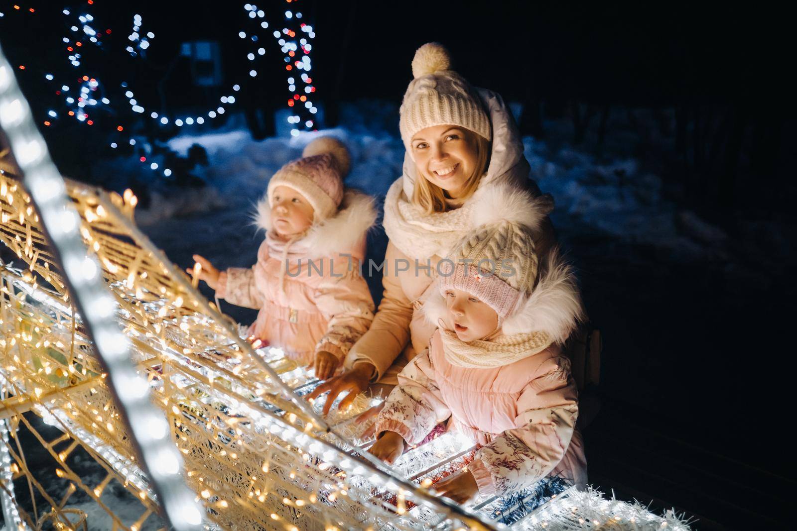 Mom and kids in the evening city with night Christmas lights.