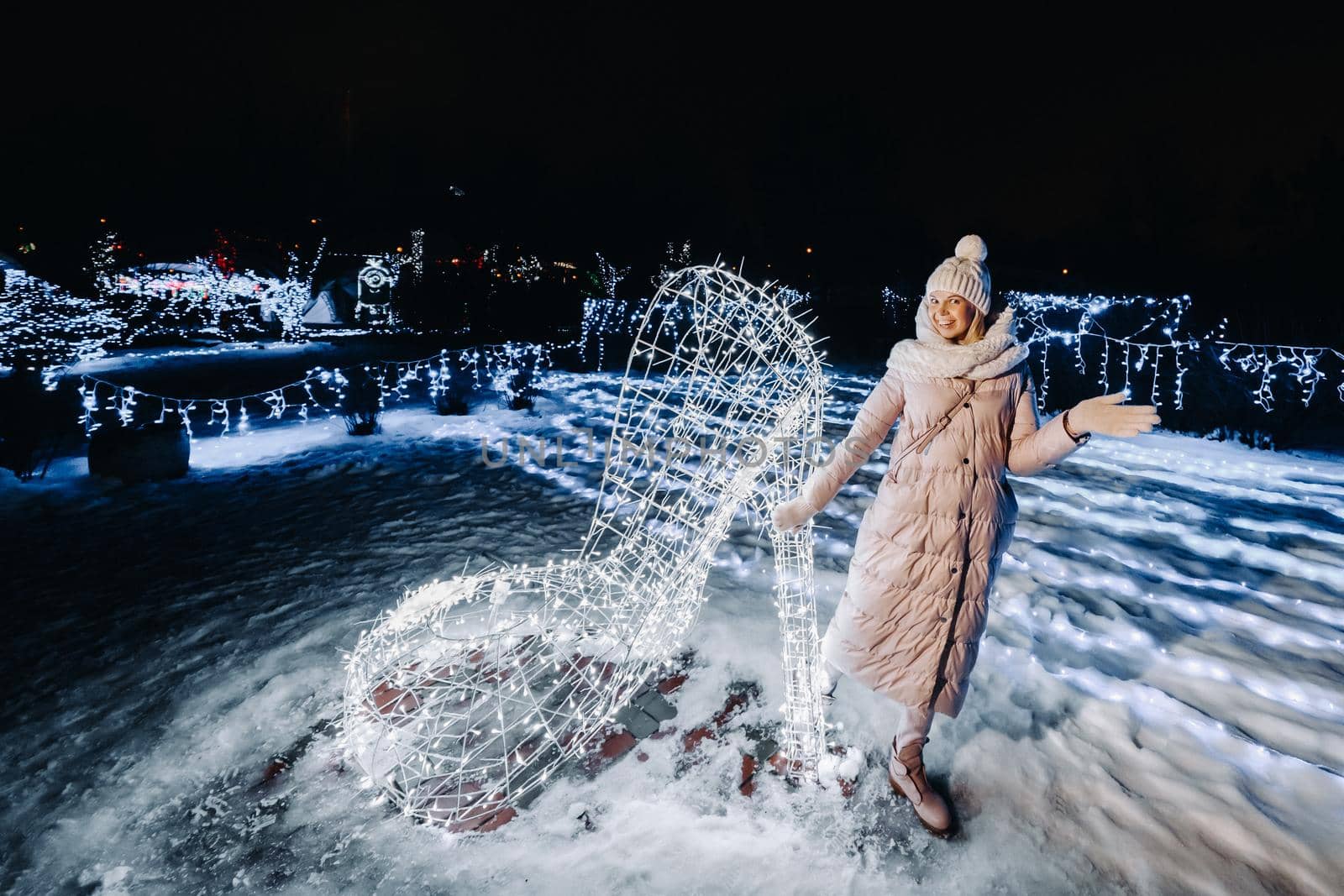 a girl in a gray jacket in winter with evening lights burning on Christmas street.