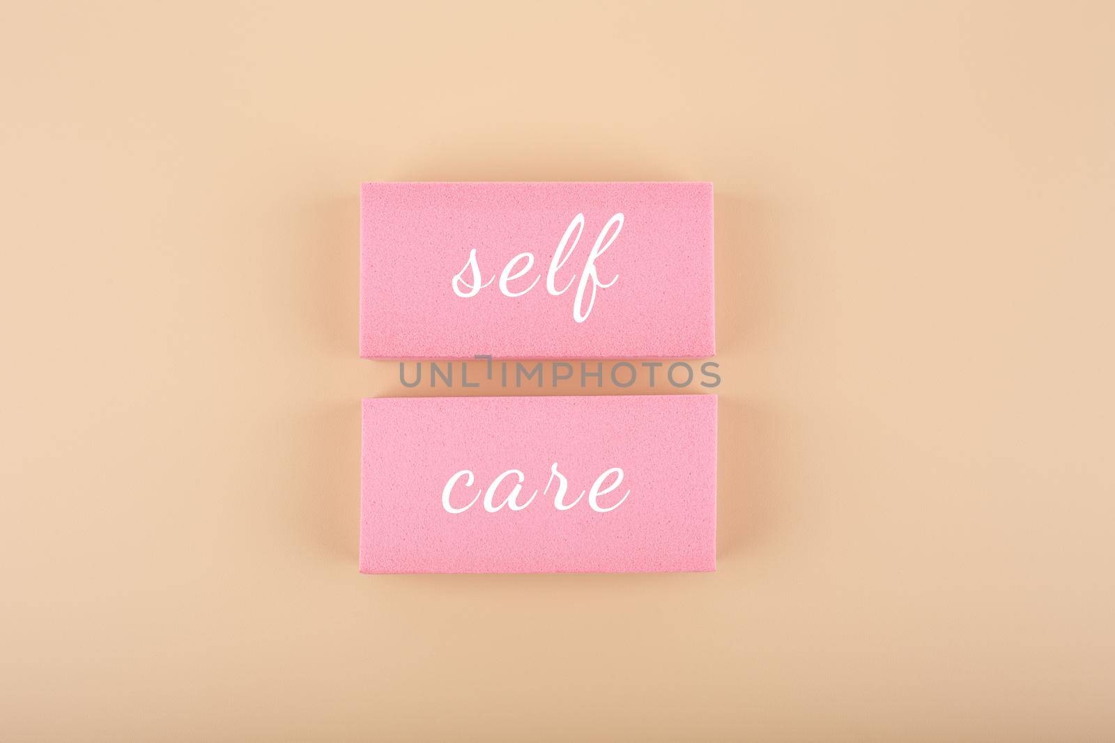 Self care, mental health, self love and acceptance concept. Hand written text on pink tablets against beige background. Trendy minimal composition