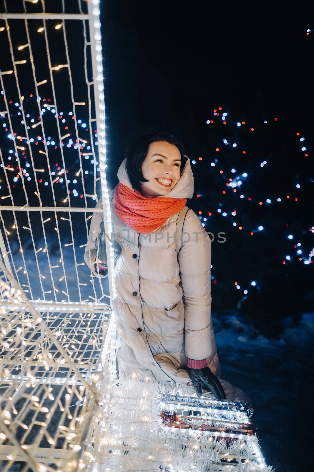 a girl in a gray jacket in winter with evening lights burning on Christmas street.