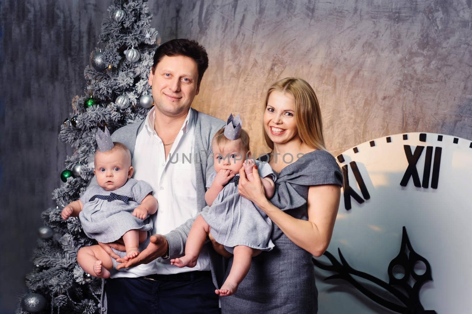 A happy big family with twin children in the New Year's interior of the house on the background of a Christmas tree.