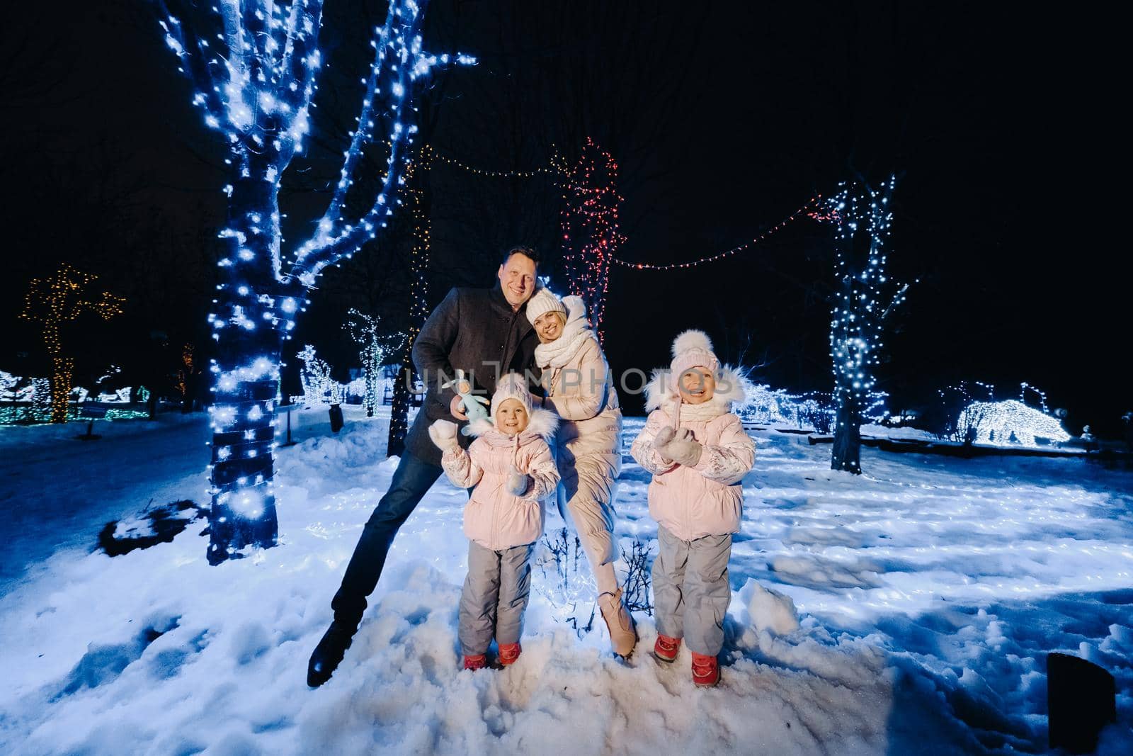 A large family with children in a Christmas city at night with night lights.