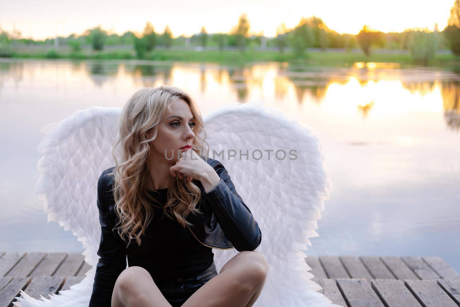 dark angel. blonde sexy woman in black leather clothes with white angels wings.