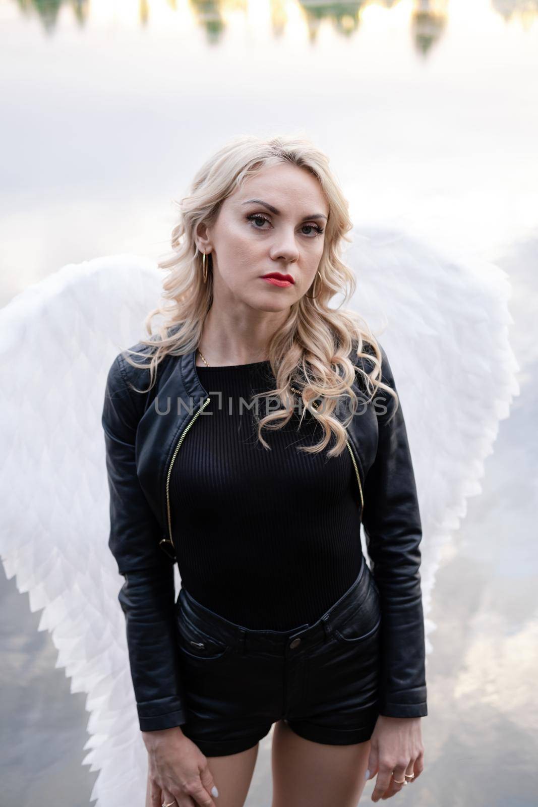 dark angel. blonde sexy woman in black leather clothes with white angels wings.