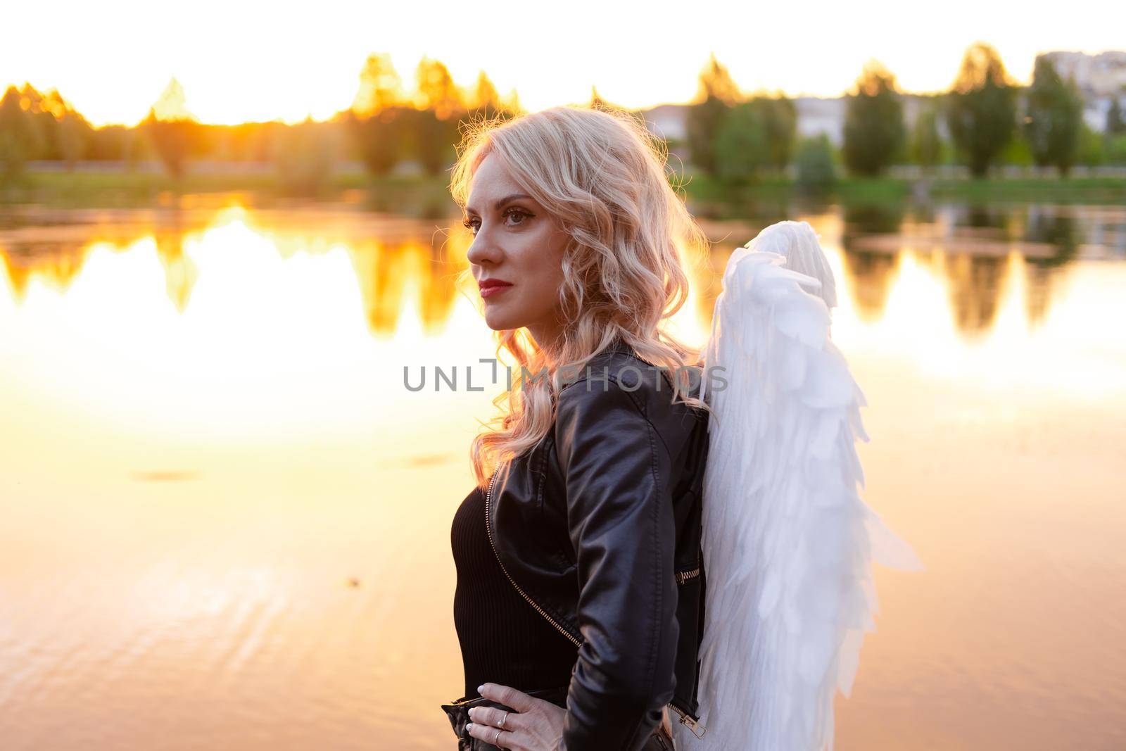 dark angel. blonde sexy woman in black leather clothes with white angels wings.