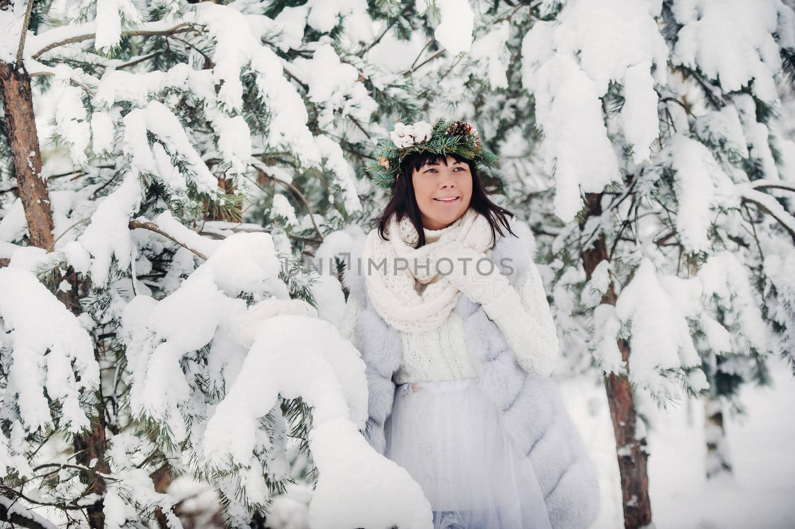 Portrait of a woman in white clothes in a cold winter forest. Girl with a wreath on her head in a snow-covered winter forest by Lobachad